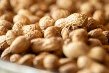 amendoins com casca vista de perto. Os amendoins são de cor marrom. Eles estão dispostos em uma pilha irregular, com alguns amendoins inteiros e outros quebrados.