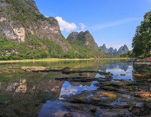 Karst mountains landscape on the Li River with reflection and stony foreground. Yangshuo, Guilin, Guangxi, China.