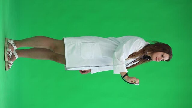 woman doctor on green background. holding a statoscope
