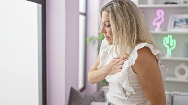 Young blonde woman suffering heart pain at home