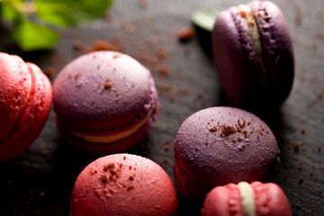 Colored macaroons. Delicious sweet colorful French desserts on black background