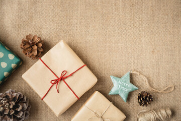 Christmas wrapped gifts, decorations and spruce cones are on the canvas background in the corner of the image. Retro style. Copy space.