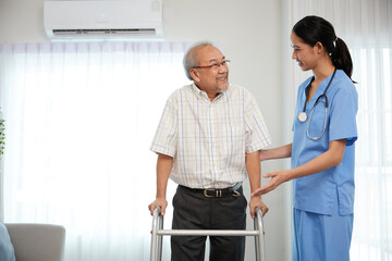 nurse or caregiver helping senior man walking with a walker and support him at home