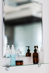 hygiene, beauty and daily routine concept - close up of lotion, perfume and moisturizer on mirror shelf in bathroom