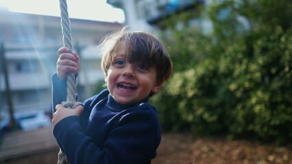 Heartwarming Close-Up of Joyful Child Sliding on Wire Rope Between Trees, Nostalgic Park Fun. Young...