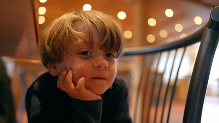 Hungry Anticipation of Cheerful Boy Sitting with hand in chin, Patiently Awaiting Meal in Restaurant