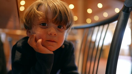 Hungry Anticipation of Cheerful Boy Sitting with hand in chin, Patiently Awaiting Meal in Restaurant