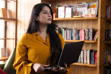 Beautiful young business woman girl student studying or explaining on video call on laptop in school or collage library or working in corporate office searching for information on internet or books