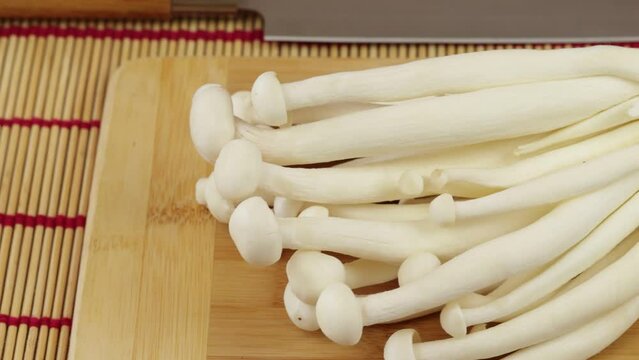 plusieurs champignons enoki crus, en gros plan, dans un plat