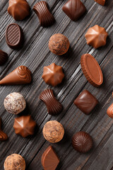 Assorted chocolates on dark wooden background top view