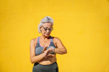 Elder serious sportive woman using a smartwatch