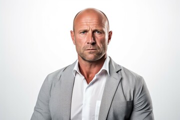 A bald man wearing a gray jacket and white shirt stands confidently.