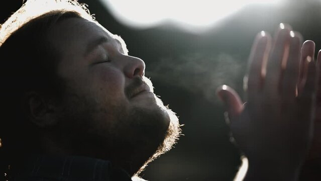 Faithful disciple in prayer outdoors in sunlight with flare. Person asking for help during difficult times