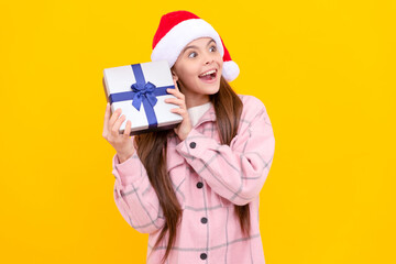 amazed child in santa claus hat hold present box on yellow background, shopping