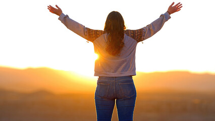 Young woman standing on a cliff at Grand Canyon and raising her arms from a feeling of infinite...