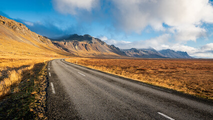 Fototapeta na wymiar Route ensoleillée sur fond de montagne en Islande