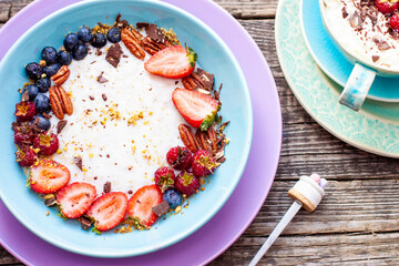 Greek yogurt bowl with fresh berries, strawberry, raspberry, blueberry and pecan nuts isolated on rustic background, top view