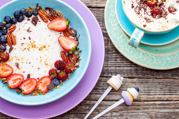 Greek yogurt bowl with fresh berries, strawberry, raspberry, blueberry and pecan nuts isolated on rustic background, top view