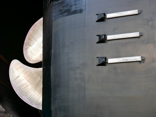 black gold. ship in dry-dock out of water. bronze polished propeller on black painted hull, details...