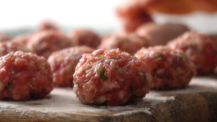 Close-up shot of Raw Handcrafted Meatballs on Wooden Board with a shallow depth of field.