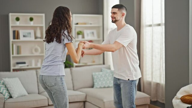 Life’s a dance! beautiful couple, glowing with confident love, joyously smiling & dancing together at home, in their cozy living room. all in casual fashion, enjoying the music. happy times!