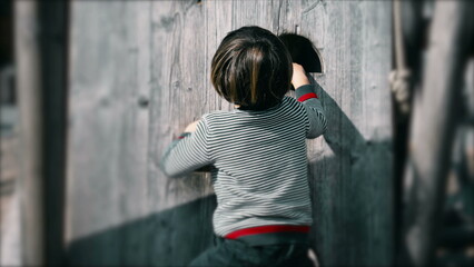 Child climbing playground structure, small boy exercising at public park during autumn fall season