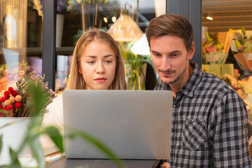 A woman and a man look at the computer in a flower shop