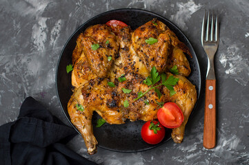 Chicken tabaka, national Georgian dish. Whole chicken with a golden fried crust sprinkled with parsley on a dark background, horizontal.
