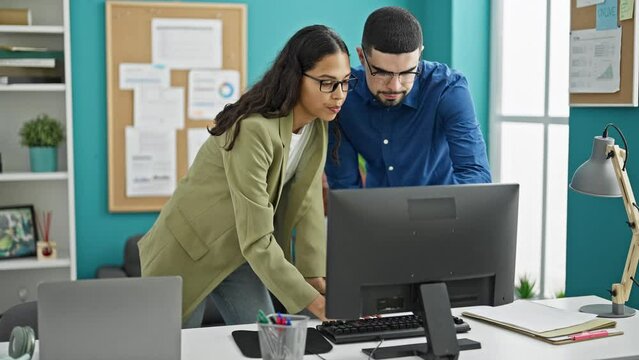 Dynamic duo at work, two professional workers, man and woman, conjuring success at their desk inside office, harnessing technology with computer