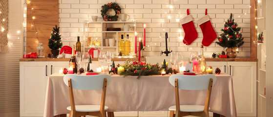 Festive table setting with Christmas decorations and glowing lights in kitchen at evening