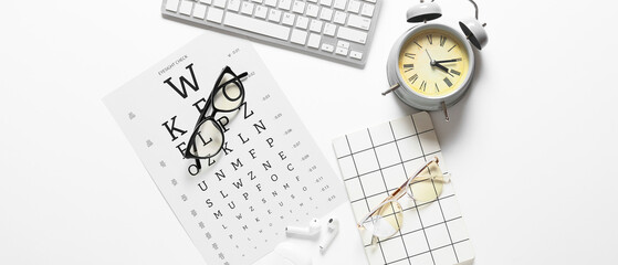 Eyeglasses, alarm clock, notebook and eye test chart on white background
