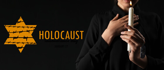 Young woman with candle and military dog tag praying on black background. International Holocaust...