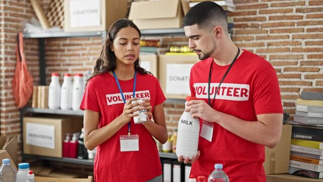 Man and woman volunteers, united in service, diligently checking box of donated products at the heart of charity center