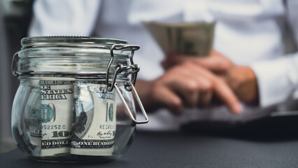 Fototapeta premium Man hands counting expenses banknotes of dollar cash on calculator. Close up of hands unrecognizable Businessman. Save up budget investment concept. American bucks fund savings