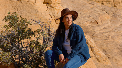 Naklejka premium Young woman in western outfit enjoying the tranquility in a canyon of the Nevada desert - travel photography