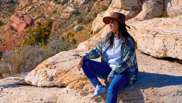 Young woman in a western style outfit sitting on a rock in the Nevada desert - travel photography
