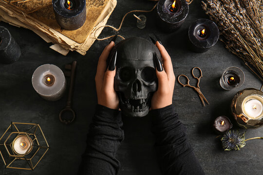 Witch with skull on dark table