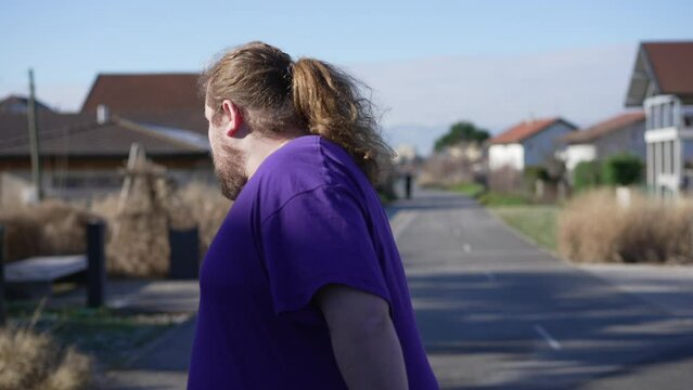 One young determined overweight man running outdoors. A fat person getting back into fitness. Back tracking shot. Motivational sport concept