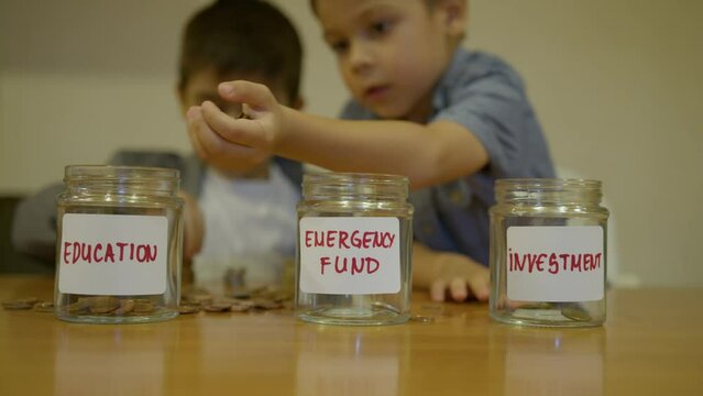 Budgeting and investment in education. Early financial literacy. Boy puts coind in the jar for education. High quality 4k footage