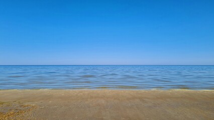 Fototapeta na wymiar Clear blue sky over the sea and the sandy shore of the beach