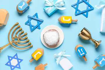 Hanukkah composition with dreidels, donut, David stars and menorah on blue background