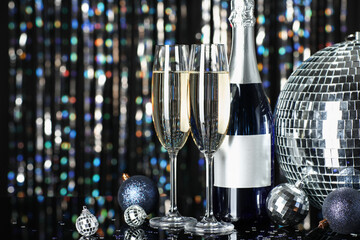 Festive New Year party composition with bottle and glasses of champagne, decorative disco balls and...
