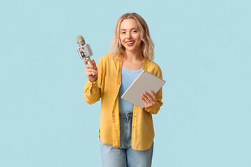 Portrait of female journalist with microphone and clipboard taking interview on blue background