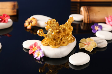 Obraz na płótnie Canvas Golden Chinese Dragon figurine with beautiful flowers and pebbles on reflective surface, closeup. New Year celebration