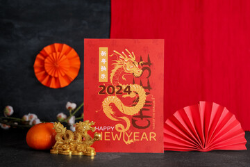 Golden dragon figurine with greeting card and traditional Chinese decor on black table. New Year celebration