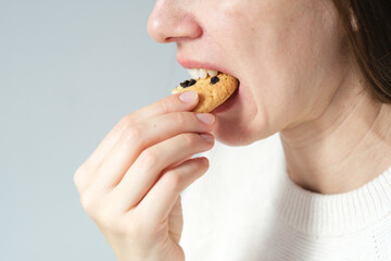 Close up an unrecognizable woman bite bite of healthy muesli cookie, traditional and popular...