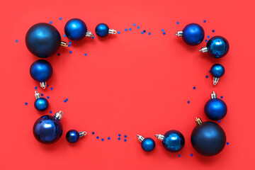 Composition with frame made of blue Christmas balls with sparkles on red background