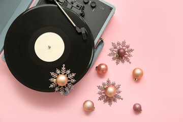 Vintage turntable with Christmas decorations on pink background
