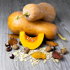 Image of pumpkin and autumn leaves on a wooden surface providing space for products or...
