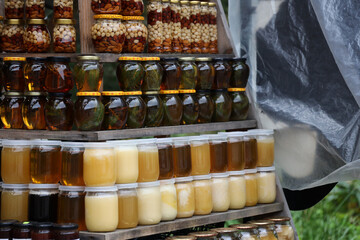 Jars of different honey varieties stocked on a shelf. Lavender, linden and mixed honey close up